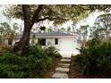 Well-kept home featuring an attached garage and a stone pathway leading through landscaped foliage at 8570 Tropicaire Blvd, North Port, FL 34291