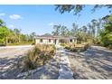 Well-manicured circular driveway leads to a charming home nestled among mature trees at 8570 Tropicaire Blvd, North Port, FL 34291