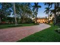 Elegant brick driveway leading to a luxurious home surrounded by lush greenery and palm trees at 1067 Westway Dr, Sarasota, FL 34236
