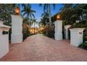 Grand gated entrance with brick driveway, lush landscaping, and stately pillars with lanterns at 1067 Westway Dr, Sarasota, FL 34236