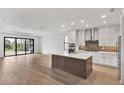 Open-concept kitchen with stainless steel appliances, a center island, and hardwood floors for a modern design at 12719 Sunbridge Dr, Venice, FL 34293