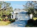 Home featuring mature landscaping, an attached two-car garage, and a charming white exterior at 8134 Coates Row Pl, Bradenton, FL 34201