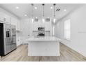 Bright kitchen featuring white cabinets, stainless steel appliances, and a large island with pendant lighting above at 26936 Lark Ct, Punta Gorda, FL 33955