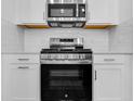 Close-up of a stainless steel range and microwave above white cabinets and drawers in a bright, modern kitchen at 26936 Lark Ct, Punta Gorda, FL 33955