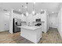 Bright kitchen featuring white cabinets, stainless steel appliances, and a large island with pendant lighting above at 26936 Lark Ct, Punta Gorda, FL 33955