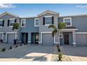 Townhouse exterior showcasing a well-maintained gray facade, paired garages, and tropical landscaping at 2838 Newbern Banks Dr, Bradenton, FL 34208