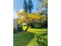 Beautiful home exterior featuring green lawn, a flowering tree and lush landscaping under a sunny blue sky at 3417 Tallywood Ln, Sarasota, FL 34237