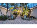 Elegant gated entrance framed by tropical landscaping, with a brick path leading to the main entrance of the home at 4473 Gulf Of Mexico Dr, Longboat Key, FL 34228