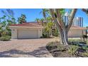 Beautiful home featuring a two-car garage and a brick driveway, surrounded by lush tropical landscaping and mature palm trees at 4473 Gulf Of Mexico Dr, Longboat Key, FL 34228