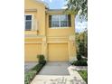 A charming yellow townhome with two garage doors, tasteful landscaping, and a cozy balcony on the second floor at 6768 Breezy Palm Dr, Riverview, FL 33578
