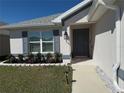 Inviting front entrance with gray front door, shutters, professional landscaping, and stone-lined flower beds at 2556 Averland Loop, North Port, FL 34287