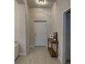Tiled hallway with decorative console table and neutral paint, leading to various rooms in the home at 2556 Averland Loop, North Port, FL 34287