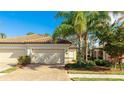 Two car garage and brick driveway with landscaping and beautiful blue skies at 20170 Benissimo Dr, Venice, FL 34293
