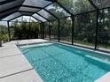 A screened in in-ground pool is surrounded by tropical foliage and a black metal fence at 5821 Hevena Ct, Palmetto, FL 34221