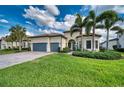 Charming home features a well-manicured lawn, palm trees, and a paver driveway at 7760 Grande Shores Dr, Sarasota, FL 34240
