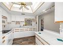 Well-lit kitchen boasting white cabinets, tile countertops, and wood-look floors at 1022 De Soto Dr, Dunedin, FL 34698