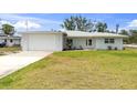 Charming single-story home boasts a lush green lawn, a freshly painted white exterior, and an attached garage at 400 Dona Dr, Nokomis, FL 34275