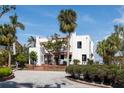 Charming white home featuring a red tiled roof, lush landscaping, and mature palms at 679 Norsota Way, Sarasota, FL 34242
