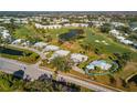 Aerial view of home in a golf community, surrounded by lush greenery, and a tranquil pond at 276 Cerromar Way # 60, Venice, FL 34293
