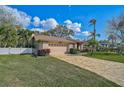 Attractive single-story home featuring a tan exterior, brick driveway, and lush green lawn with mature landscaping at 4639 Meadowview Cir, Sarasota, FL 34233