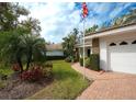 Landscaped front yard with lush greenery and brick pathway leads to a charming home with a two-car garage at 5642 Garden Lakes Dr, Bradenton, FL 34203