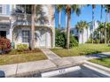 Front exterior of a townhome with manicured lawn, sidewalk, and mature palm trees at 4717 Sabal Key Dr, Bradenton, FL 34203