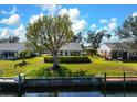 Charming waterfront home with a private dock, lush lawn, and mature trees under a sunny sky at 4721 Mount Vernon Dr, Bradenton, FL 34210