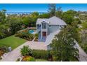 Beautiful aerial view of charming two-story home with a pool, brick driveway, and lush landscaping at 501 Reclinata Dr, Longboat Key, FL 34228