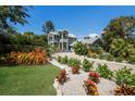 Stunning two-story home boasting vibrant landscaping, lush green lawn, and a brick driveway at 501 Reclinata Dr, Longboat Key, FL 34228