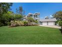 Well-manicured front lawn, mature trees, and lush landscaping of this charming two-story home at 501 Reclinata Dr, Longboat Key, FL 34228