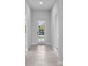 A bright and inviting hallway featuring tile flooring and a door with glass panels that provides natural light at 8071 Slipway Dr, Sarasota, FL 34240