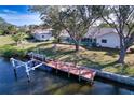 Backyard view with a private pool area, screen enclosure, and a wooden dock extending into the waterway at 18576 Alphonse Cir, Port Charlotte, FL 33948