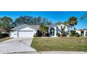 Charming single-story home with a well-manicured lawn, two-car garage, and beautiful landscaping at 18576 Alphonse Cir, Port Charlotte, FL 33948