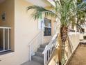 Exterior shot of a charming condo with stairs leading to the entrance, complemented by a palm tree at 2424 Placida Rd # C104, Englewood, FL 34224