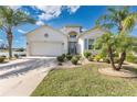 Inviting single-Gathering home featuring a lush front yard, palm trees, and a spacious driveway at 3831 Creekside Park Dr, Parrish, FL 34219