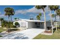 Well-maintained single-story home with carport, manicured lawn, and tropical landscaping with several tall palm trees at 8449 Imperial Cir, Palmetto, FL 34221