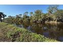 Scenic water view, lined with lush vegetation and mature trees on a clear day at 9478 Prospect Ave, Englewood, FL 34224