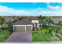 Beautiful single-Gathering home with a three-car garage, tile roof, brick driveway, and lush tropical landscaping at 16741 Ellsworth Ave, Bradenton, FL 34202