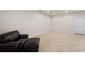 Bright living room with ceramic tile floors, a white door and a brown leather ottoman at 5435 Soapstone Place # 22-103, Sarasota, FL 34233