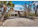 Inviting exterior view showing the stilt construction with a driveway and lush tropical landscaping at 650 Penfield St, Longboat Key, FL 34228