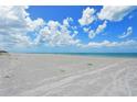 Expansive beach with white sand leading to a calm, blue ocean under a bright sky with fluffy white clouds at 8764 Midnight Pass Rd # A301, Sarasota, FL 34242