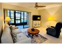 Bright living room features neutral decor, ceiling fan, and sliding glass doors to the lanai at 1515 Forrest Nelson Blvd # P107, Port Charlotte, FL 33952