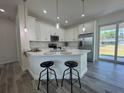 Modern kitchen features white cabinetry, stainless steel appliances, and island with bar seating and pendant lights at 18290 Grace Ave, Port Charlotte, FL 33948
