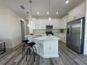 Modern kitchen features white cabinetry, stainless steel appliances, and island with bar seating and pendant lights at 18290 Grace Ave, Port Charlotte, FL 33948