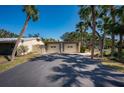 Home exterior featuring a spacious driveway leading to a two-car garage, surrounded by lush palm trees and blue sky at 231 Hourglass Way # V5, Sarasota, FL 34242