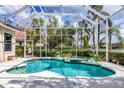 Screened-in pool with attached spa, lush tropical landscaping, and backyard lake views at 6922 Stanhope Pl, University Park, FL 34201