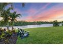 Serene backyard view with comfortable chairs, lush greenery, and a tranquil lake at sunset at 8284 Barton Farms Blvd, Sarasota, FL 34240