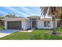Charming single-story home with a well-manicured lawn, a gray garage door, and a modern front door at 1471 Palmwood Dr, Sarasota, FL 34232