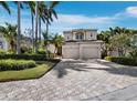 Two-story home with a two-car garage and a brick-paver driveway surrounded by lush landscaping and palm trees at 2065 Harbour Links Dr # 5, Longboat Key, FL 34228