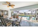 Screened in patio area featuring a ceiling fan, outdoor table and chairs, and a view of the pool and canal at 2501 W Marion Ave, Punta Gorda, FL 33950